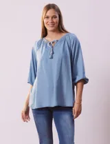 Blusa celeste de tencel marca Marissa Olivia, con cuello a la base, escote en V y lazo de ajuste. Cuello y escote calado. Manga 3/4 amplia con puño elastizado.
