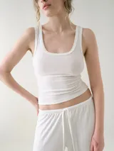Musculosa básica entallada de tela pointelle color blanco, con escote redondo y detalle de ondas en los bordes.