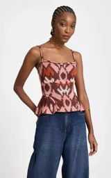 Top de punto Le Lis Blanc con tirantes finos, escote recto, ajuste ceñido al cuerpo y diseño con peplum en la parte inferior. Presenta un estampado geométrico en tonos rosado, marrón y beige.