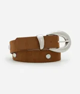 Cinturón femenino de ancho medio confeccionado en material sintético efecto gamuza color marrón. Presenta aplicaciones de tachas metálicas circulares, hebilla ovalada de metal plateado y pasador a juego.