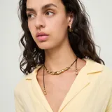 Collar de cuero marrón con detalles y colgantes en forma de gota bañados en oro.