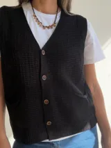 Chaleco de tejido de punto con textura, escote en V y cierre frontal con botones. Presenta dos bolsillos delanteros y terminaciones en tejido acanalado en el ruedo.