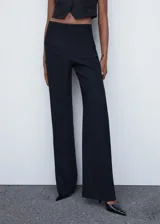 Pantalón de vestir estilo wideleg, de tiro medio y corte recto, confeccionado en tejido fluido con forro interior. Presenta bolsillos laterales y cierre oculto con botón, gancho y cremallera.