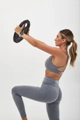 Top deportivo color beige con contorno inferior y tiras cruzadas en la espalda color borgoña. Cuenta con almohadillas removibles.