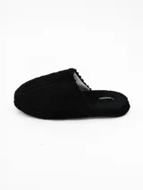 Pantuflas de estar por casa color negro, confeccionadas en tejido de pana con textura acanalada y suela plana.