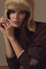 Cardigan de tejido de punto color marrón, con cuello redondo y detalle de bordado ornamental en una de las mangas. Presenta puños con textura acanalada y un acabado interior a rayas.