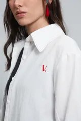 Camisa de corte holgado confeccionada en algodón tussor, con cuello clásico de tamaño ligeramente ampliado, mangas largas con pinzas laterales y puños anchos. Presenta pespuntes en color rojo a contraste y logo bordado en el pecho.