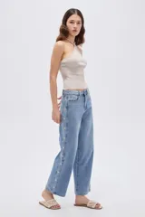 Pantalón de jean azul de corte recto y tiro medio, con detalles de estrellas bordadas a lo largo de los laterales externos de las piernas.