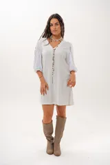 Vestido corto off-white con escote en V, de corte recto y holgado. Cuenta con mangas abullonadas tres cuartos confeccionadas en tejido broderie.
