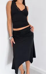 Falda midi negra de corte irregular, con detalle drapeado en la cintura.