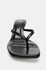 Sandalia de tacón en piel color negro, con diseño tipo thong con tira delantera para el dedo, tacón alto fino y puntera cuadrada.