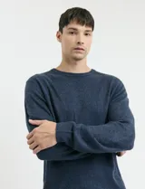 Sweater de tejido de punto con escote redondo y manga larga, con detalles de costuras en sisas y cuello. Presenta un diseño clásico y versátil.