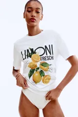 Remera blanca de manga corta y cuello redondo, con estampado central que incluye la palabra "LIMONI FRESCHI" y un racimo de limones con hojas.