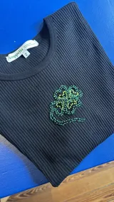 Remera corta negra de algodón elastizado con bordado de un trébol de cuatro hojas con mostacillas verdes y amarillas.