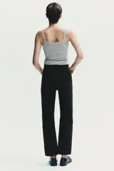 Jeans de mujer, tiro alto, color azul medio con efecto desgastado (lavado claro en muslos y oscuro en bordes). Corte recto y ancho (mom fit) con cinco bolsillos y cierre frontal de botón y cremallera.