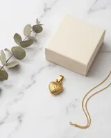 Dije en forma de corazón con diseño estriado vertical, acabado en tono dorado.