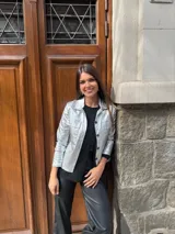 Chaqueta dorada metalizada con cuello camisero, cierre frontal con botones y bolsillos de parche en el pecho.