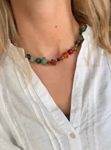Collar tipo gargantilla compuesto por piedras naturales irregulares de diversos colores intercaladas con pequeñas cuentas doradas.