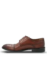 Zapato de vestir tipo Oxford con diseño brogue, confeccionado en cuero vacuno de color marrón. Presenta cierre mediante cordones, puntera redondeada con detalle de perforaciones decorativas y suela mixta de cuero y goma.
