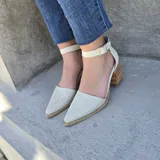 Sandalias de cuero color beige con textura sutil en la puntera afilada, taco cuadrado de madera de 6.6 cm y tira al tobillo con hebilla metálica.