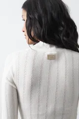 Polera de tejido de punto con textura calada y diseño de líneas verticales acanaladas. Presenta cuello alto y mangas largas con puños delicados, de silueta entallada.