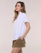 Blusa blanca de algodón texturizado con sutil relieve de rayas verticales al tono, escote en V con cuello solapa pequeño y mangas cortas.