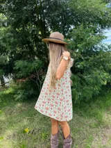 Vestido corto de lino con estampado floral en tonos rojizos y verdes sobre base clara. Presenta volados en las mangas y cierre posterior con botones forrados en la misma tela.