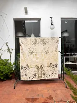 Mantel rectangular de algodón color crudo con estampado botánico en tonos marrones y verdes.