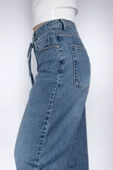 Pantalón de jean estilo mom fit en tono azul clásico, con diseño de tiro alto y lazo ajustable en la cintura. Presenta un corte relajado y holgado en las piernas, confeccionado en denim rígido con estructura.