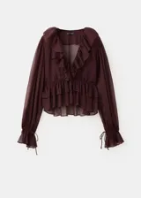Blusa fluida color bordó, con escote en V, mangas largas con volantes en los puños y detalles de volantes en el frente y el cuello.