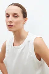Blusa de satén color blanco, sin mangas, con cuello redondo y diseño fluido.