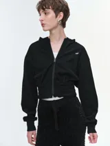 Campera deportiva cropped con capucha y cierre frontal. Presenta cintura y puños elastizados, diseño de manga larga y calce holgado en la parte superior.