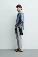 Camisa de corte regular fit confeccionada en tejido ligero de algodón, con estampado de cuadros en tonos azules y grises. Presenta cuello abotonado, manga larga con puños abotonados, bolsillo plastrón en el pecho y cierre frontal de botones.