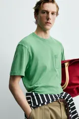 Camiseta de corte regular con cuello redondo, manga corta y bolsillo plastrón en el pecho. Presenta un acabado de color verde con efecto lavado.