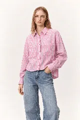 Camisa de manga larga con diseño de rayas verticales en tonos rosado y blanco, corte holgado y bolsillos frontales con solapa en el pecho.