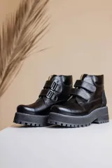 Botas cortas de cuero negro con ajuste mediante hebillas y suela track.