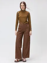 Pantalón de tiro medio y pierna ancha confeccionado en denim de algodón grueso. Presenta un diseño a rayas verticales en tonos azul y celeste, con costuras en contraste color rojo, bolsillos laterales tipo cargo y remaches metálicos.