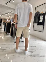 Bermuda de jean corte skinny en color beige, con diseño clásico de cinco bolsillos y cierre frontal con botón y cremallera.