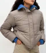 Campera puffer Marfinno con estampa de cuadros mini en tonos beige y negro, de corte recto, cuello alto y cierre frontal con cremallera. Cuenta con mangas largas y forro interior.