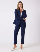 Blazer sastrero entallado color beige, con cuello de solapa, cierre frontal con un botón a tono y hombreras estructuradas. Presenta bolsillos laterales con solapa y forro interno.