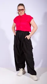 Pantalón parachute negro de corte ancho, con cintura alta ajustable con cordón, bolsillos laterales y bolsillos cargo en las piernas.