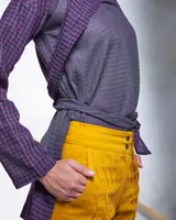 Pantalón babucha color beige de algodón, con corte a la cintura y piernas levemente amplias. Presenta textura de tablitas centrales y elásticos con broches inferiores que ajustan las piernas al tobillo.