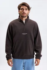 Buzo de polar color marrón con cuello alto y cierre frontal parcial. Presenta un bolsillo frontal tipo canguro y un estampado pequeño en el pecho con el texto 'NORTHERN ADVENTURES'. Cuenta con puños elásticos.