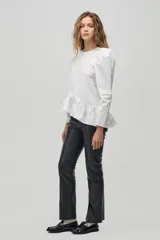 Blusa blanca de algodón con mangas largas abullonadas y peplum asimétrico con volantes.