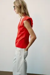Top rojo de popelín con escote en V pronunciado, mangas sisa y pespuntes en contraste. Cuenta con tirantes finos cruzados y lazada en la espalda.