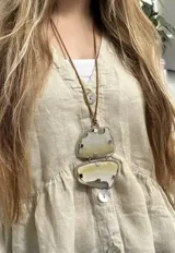 Collar largo con cordón de cuero sintético marrón y doble dije de nácar engarzado en alpaca con diseño orgánico.