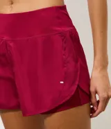 Short runner deportivo 2x1 de microfibra color bordó, con cintura elástica, bolsillo funcional con cierre y bajo redondeado.