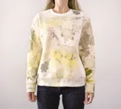 Buzo deportivo unisex color crema con estampado de hojas y manchas de colores.