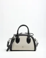 Cartera tipo baúl bicolor, combinando cuerpo de lona beige con detalles de símil cuero negro en las asas, bordes y correa. Cuenta con doble asa de mano, cierre superior y correa ajustable y desmontable para usar al hombro o cruzada.