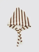 Pañuelo de tejido suave con diseño triangular, estampado a rayas verticales marrones y blancas. Se anuda al frente con un broche metálico dorado que ajusta las puntas.